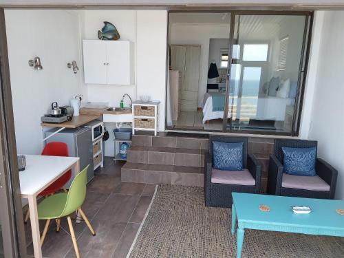 cocina y sala de estar con mesa y sillas. en Captain Sunshine Guest House en Jongensfontein