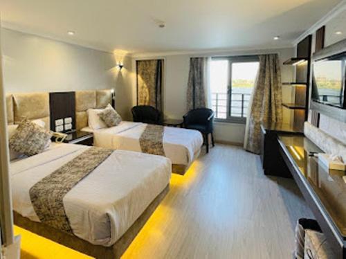 ルクソールにあるLuis Luxor Nile Cruiseのベッド2台とデスクが備わるホテルルームです。