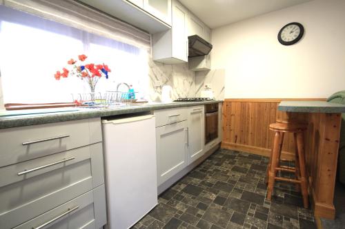 una cocina con armarios blancos y un reloj en la pared en 23 Fairfield en Inverness