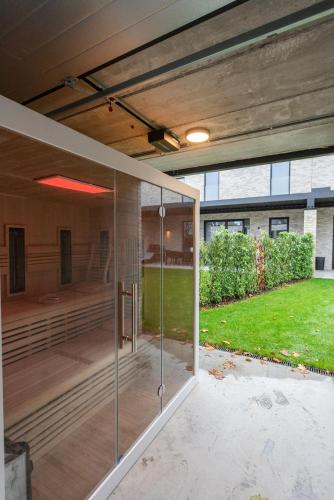 a glass extension of a house with a lawn at NIEUW De Grenspaal ZUID 2slpk - 4P - SAUNA - LAADPAAL in Riemst