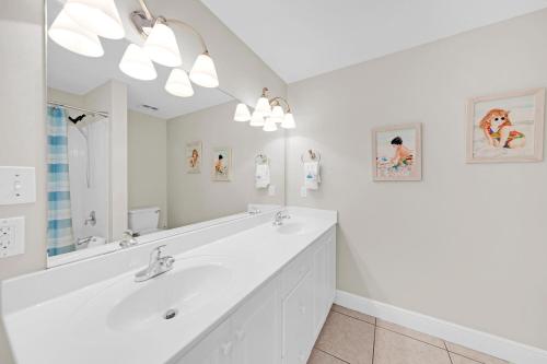 a white bathroom with a sink and a large mirror at Celadon 302 in Panama City Beach