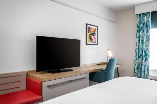 a room with a desk with a television and a chair at Hilton Garden Inn West Palm Beach Airport in West Palm Beach