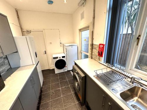 a kitchen with a sink and a washing machine at Bluebells of Kathleen near Birmingham Airport in Birmingham