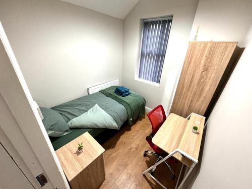 a small bedroom with a bed and a table at Bluebells of Kathleen near Birmingham Airport in Birmingham