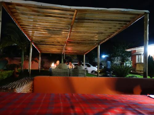 a wooden pergola with people sitting under it at night at Carpe Diem Guesthouse in Entebbe