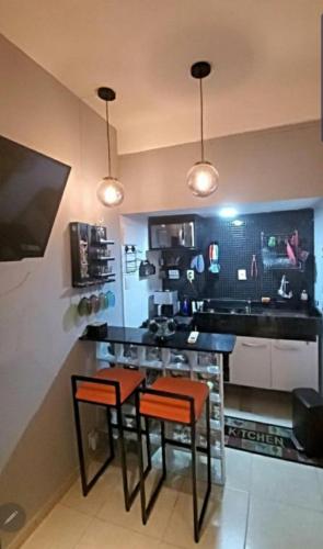 a kitchen with two bar stools and a counter at StudioRD Copacabana 250m da praia esquina com a Rua do Copacabana Palace Rodolfo Dantas in Rio de Janeiro