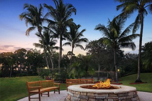a fire pit in a park with two benches and palm trees at Hyatt Vacation Club at Coconut Cove in Bonita Shores