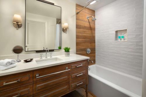 uma casa de banho com um lavatório, uma banheira e um espelho. em Hyatt Vacation Club at Coconut Cove em Estero