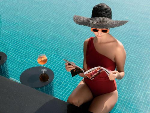 a woman in a swimsuit and hat sitting in a swimming pool at Sofitel Dubai The Obelisk in Dubai