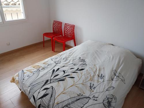 1 dormitorio con 2 sillas rojas y 1 cama en centre historique et proche mer, en Sigean