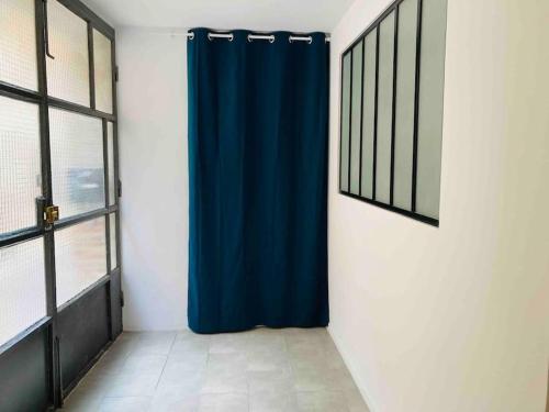 - un rideau de douche bleu dans une chambre avec fenêtres dans l'établissement Village apartment with character, à Saint-Hippolyte