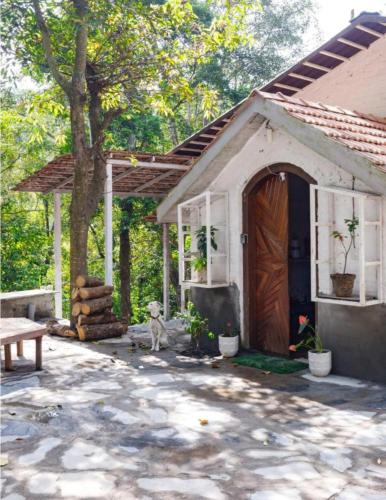 a dog sitting in front of a house with a door at Jungle stay by Bilwa Estate in SanivÄrsante
