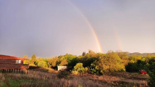 a rainbow over a field with a house and a barn at Merry Mongoose Riverside Tent in Skeerpoort