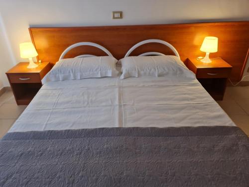 a large white bed with two lamps on two tables at B&B L' Oasi in Chiatona
