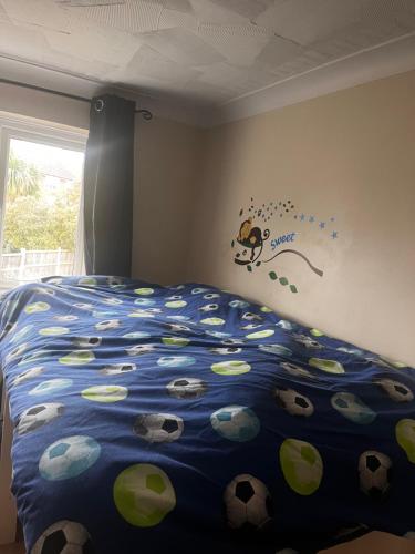 um quarto com uma cama com um edredão azul com bolas de futebol em No name 