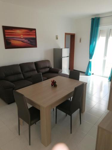 ein Wohnzimmer mit einem Tisch und einem Sofa in der Unterkunft Casa del sole in Montalbano Ionico