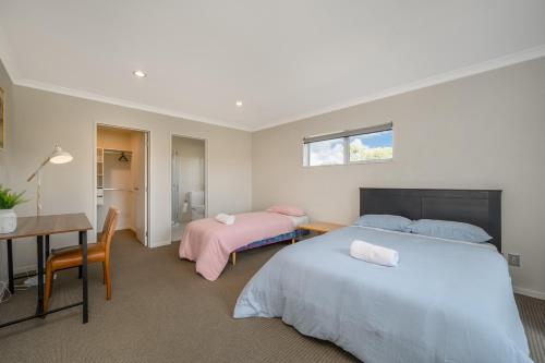 a bedroom with two beds and a desk and a table at Extra-Large Brand-New House 8 Bedrooms 6 Bathrooms in Auckland