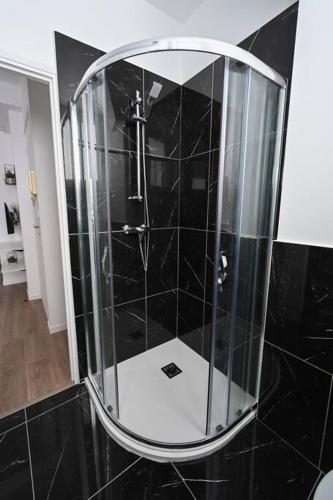 La salle de bains est pourvue d'une douche en verre et de carrelage noir. dans l'établissement Le Petit Cocon - Docks Vauban, au Havre