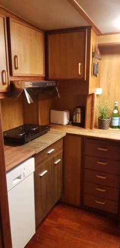 una cocina con armarios de madera y electrodomésticos blancos en M/S Furusund, en Furusund