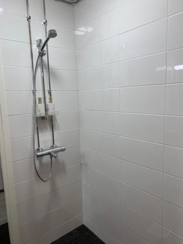a shower in a bathroom with white tiles at Yksiö keskustassa saunalla in Iisalmi