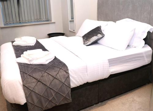 a bed with white sheets and black and white pillows at Kest Cozy Apartment in Leeds! in Leeds