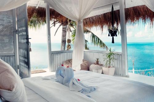 een slaapkamer met een bed en uitzicht op de oceaan bij Tropical Glamping Nusa Penida - Private Romantic Seaside Bungalow Diamond Beach in Nusa Penida