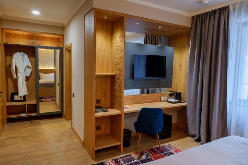a hotel room with a bed and a tv and a room at Dami Almaty Hotel in Almaty