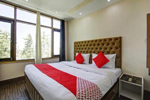 a bedroom with a large bed with red pillows at OYO Flagship The Green Park Shimla in Shimla