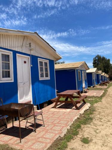 una fila de casas azules con una mesa de picnic y un banco en Cabañas San Carlos, en Las Cruces