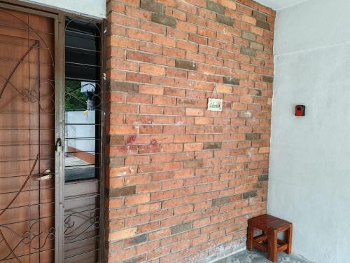 a brick wall with a door and a wooden stool at OneB Homestay Shah Alam, 9 pax, I-city near, Wifi in Shah Alam