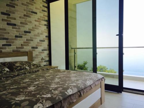 a bedroom with a bed and large windows at Apartment SuperSeaView in Sutomore