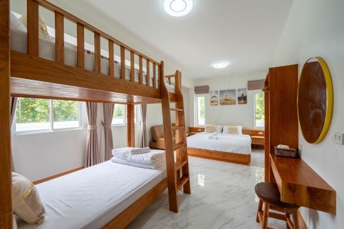 a bedroom with two bunk beds and a desk at บ้านลินลดา พูลวิลล่าขนอม in Ban Phang Phrao