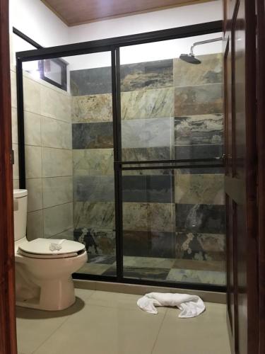a bathroom with a toilet and a glass shower at La Fortuna Donwtown Dreams in Fortuna