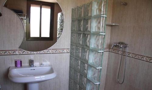 y baño con lavabo, espejo y ducha. en La Tellería en Valjunquera