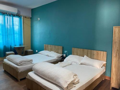 2 camas en una habitación con una pared azul en Namaste Hotel, en Ataria