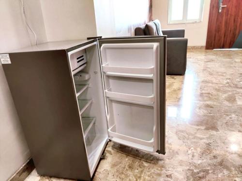 an empty refrigerator with its door open in a room at Luxury Family Suite Homestay in Vrindavan with Lobby, Balcony, Kitchen, Washing Machine - Free Wifi, No Parking in Vrindāvan