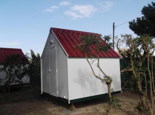 a smallshed with a red roof in a yard at Solmeco Park in Aldeia do Meco