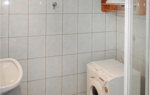 a white tiled bathroom with a washing machine and a sink at Cozy Apartment In Klein St, Paul With Kitchen in Eberstein