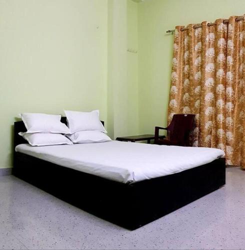 a bed with white sheets and pillows in a bedroom at RN Residency in Varanasi