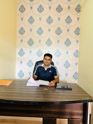 a man sitting at a desk with a book at RN Residency in Varanasi