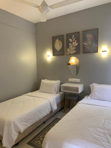 Habitación con 2 camas, mesa y 2 lámparas en DNAURA HOMESTAY BATU BURUK TERENGGANU, en Kuala Terengganu