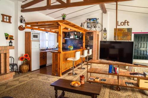 ein Wohnzimmer mit einem großen TV und einer Küche in der Unterkunft Apartamento Loft La Encina in Torrejón el Rubio