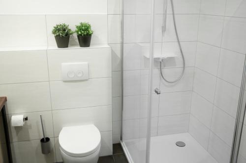 a bathroom with a toilet and a shower with two plants at Landgasthof Obersteberg in Sprockhövel