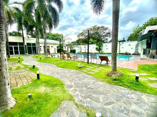 une cour avec une piscine et des palmiers dans l'établissement Hotel Euroasia By BLUEBOOKERS, à Ángeles