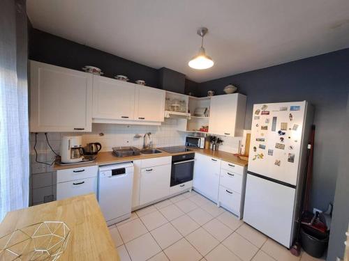 une cuisine avec des armoires blanches et des appareils électroménagers blancs dans l'établissement Le Ces-Spacieuse maison - Wifi Jardin - Parking gratuit - 15min des plages, à Béziers