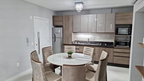 eine Küche mit einem weißen Tisch und Stühlen in der Unterkunft Areias de Bombas in Bombinhas