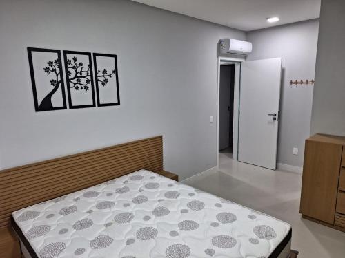 ein Schlafzimmer mit einem Bett und zwei Bildern an der Wand in der Unterkunft Areias de Bombas in Bombinhas