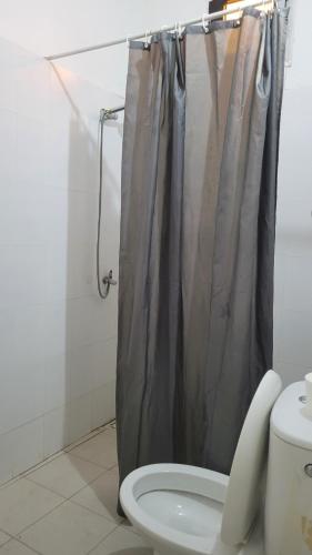 a bathroom with a shower curtain and a toilet at Lowéne in Guediawaye
