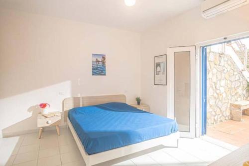 Un dormitorio blanco con una cama azul y una ventana en Giglio Verde 2, en Isola del Giglio