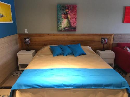 a bedroom with a bed with blue pillows and a painting at Apart Gallery - San Lorenzo - Salta in Salta